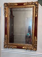 Front view of rectangular mirror with ornate gilt frame and red insets