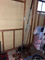 Photo of Olympic barbell, non-Olympic barbell, and assorted weight plates stacked on floor against basement wall