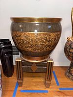 Front view of the large ceramic planter on wooden stand showing decorative body and stand details.