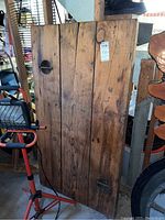 Full view of the wooden plank showing its structure and signs of wear, including embedded metal hardware typical of ship doors.