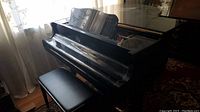 Black Yamaha baby grand piano with bench on patterned rug