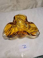 Amber pulled glass bowl showing tri-lobed shape and clear glass highlights.