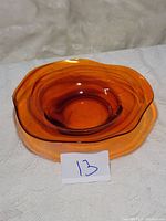 Photo of an amber-colored glass plate with wavy edges placed on a white textured surface.