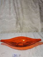 Amber Viking glass oval bowl placed on white cloth with soft fur-like background, showing full profile of bowl including length and depth visually.
