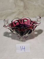 Front view of the cranberry color Murano glass bowl with two candlestick holders on sides.