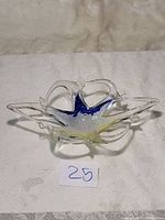 Clear Murano Lavorazione pulled art glass candy bowl dish with star-shaped form and blue and yellow glass accents on a white surface.