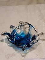 Side angle of blue and clear art glass basket highlighting the organic, flowing rim and textured base