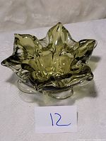 Green mid century Murano blown glass bowl with wavy edge shape shown on white fabric background with the lot number card.