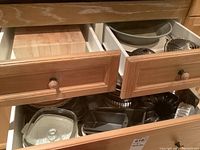 Open drawer photo showing glass and metal baking pans including springform pans and ceramic pie plates