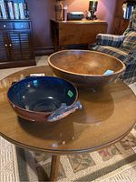 Photo showing both wooden butter bowl and signed pottery bowl with fish handles on round table