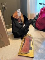 Three angel wall hangings, two inside a bag and one on floor, showing detailed religious artwork with gold backgrounds