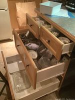 Image of open kitchen drawers with visible Pyrex glass casseroles, blender pitcher, and metal tart flan molds inside, plus nested cookie cutters.