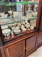 Full view of tea set, decanter, sherry glasses, and etched glass items inside cabinet.