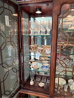 Glass cabinet displaying the various glassware and china items alongside decorative pieces