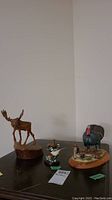 Overview of three wood animal carvings: turkey, chickadee and moose
