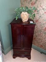 Full front view of wooden jewelry cabinet with planter on top