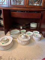 Overall view of china set in quilted bags with silverplate tray under cabinet