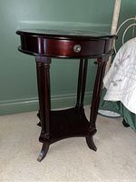 Photo of oval wood side table showing drawer and legs