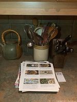 Wide view of kitchen counter with ceramic teapot, utensil crock, recipe books, and knife block