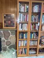 Full view of the IKEA wooden bookcase with glass doors filled with books, showing its height and storage capacity.