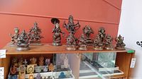 View of brass Hindu figurines on wooden shelf in front of red wall
