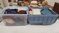 Two plastic storage totes filled with folded garments