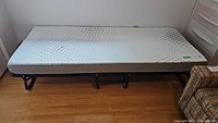 Side view of the full folding cot bed with memory foam mattress set up, showing metal frame and mattress.
