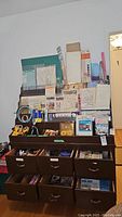 Wide shot showing the entire craft supplies storage area with cutting boards, rulers, and various sewing and crafting items arranged on shelves and in drawers.