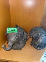 Photo showing metal elephant and peacock figurines on shelf, green paper with 5 x 8 x 6 dimensions attached to elephant