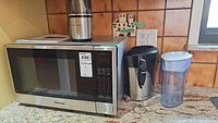 Full view of all items together including microwave, grinder, frother, and pitcher on countertop.