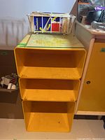 Full front view of yellow resin organizer with three compartments under a flat top surface