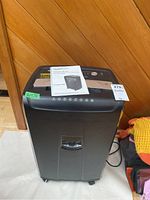 Full front view of the AmazonBasics paper shredder with instruction manual on top, showing overall condition and size.