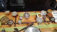 Photo showing all small pill boxes, keychain and pen-like object arranged on a flat surface.
