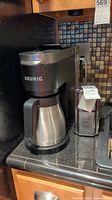 Keurig coffee maker and Cuisinart coffee grinder on kitchen counter, showing full front and side views.