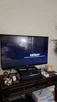 Front view of LG TV powered on showing Verizon setup screen.