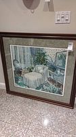 Framed print of a bedroom scene with chaise lounge, antique chair, lace curtains, plants, and side table.