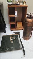 Photo showing fire extinguisher and paper cutter next to wooden shelving unit