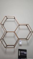 Full view of three connected hexagon metal wall art pieces mounted on a wall.
