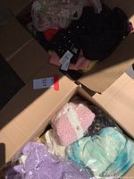 Four assorted knitwear pieces in open box, overhead view