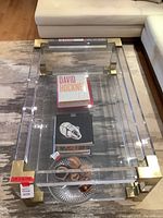 Overall perspective of the acrylic coffee table on area rug with decorative books and bowl