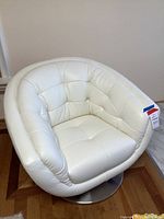 Front view of white barrel swivel accent chair showing tufted upholstery and metal pedestal base