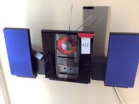 Full view of main unit between two speakers showing red volume knob, glass doors open and telescopic antenna