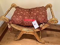 Front view of wooden bench with cushioned seat and gold painted frame.