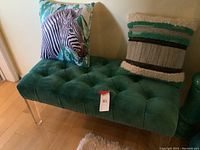 Blue velvet tufted bench with tufted seat and two decorative pillows placed on top, one with zebra print.
