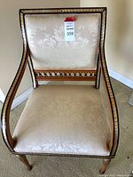 Full view of the chair showing cream damask upholstery and wooden frame with metallic painting.