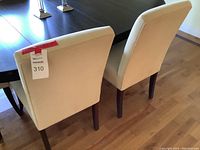 Rear view of two ivory upholstered chairs next to a dark wood table