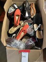 Overhead view of large cardboard box filled with assorted women’s shoes