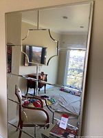 Front view of the large rectangular decorative wall mirror showing segmented design and central decorative element reflecting room interior.