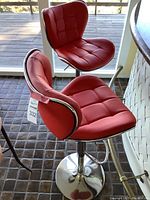 Two red tufted barstools with chrome bases side by side
