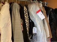 Multiple hanging garments on rod including coats, blazers, vests, sweaters